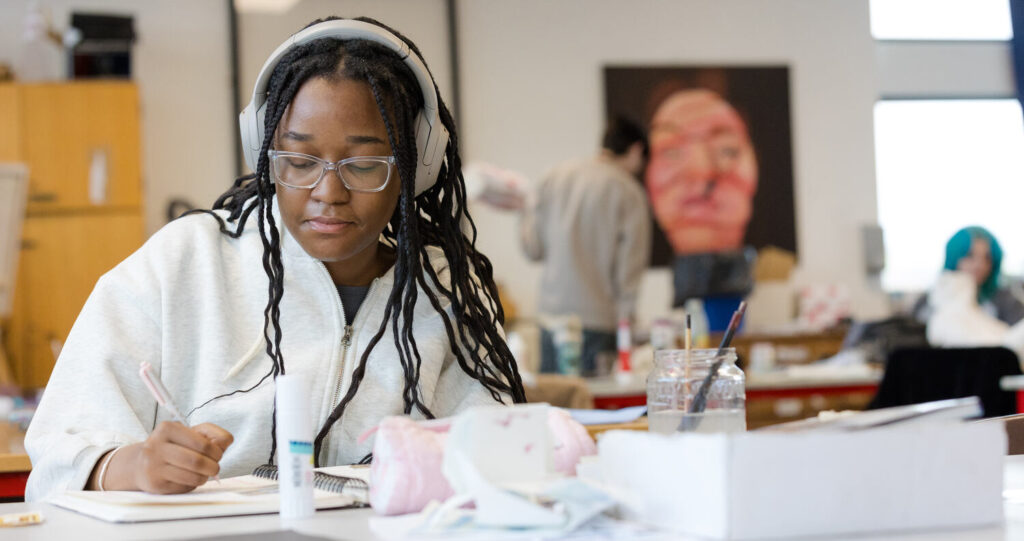 a student alone at a desk studying with her headphones on
