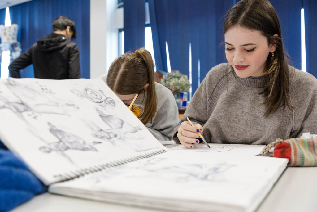 an art student in her sketchbook drawing